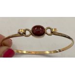 A gold bangle set with single red stone marked .375. 5.4gms total.Condition ReportGood condition.
