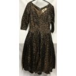A 1950's cocktail dress by Chatil, black and brown silk style fabric with collared hips, v- neck,