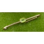 A 15ct gold bar brooch with central peridot stone. Marked to back Horsforth Golf Club 1914 15CT. 5cm
