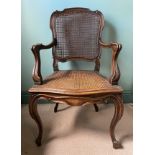 A caned armchair in the French style with carved cabriole front legs. 101 h x 60cm w.
