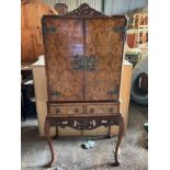 A burr walnut cocktail cabinet with decorative brass fittings. 70 w x 43 d x 159cm h on cabriole