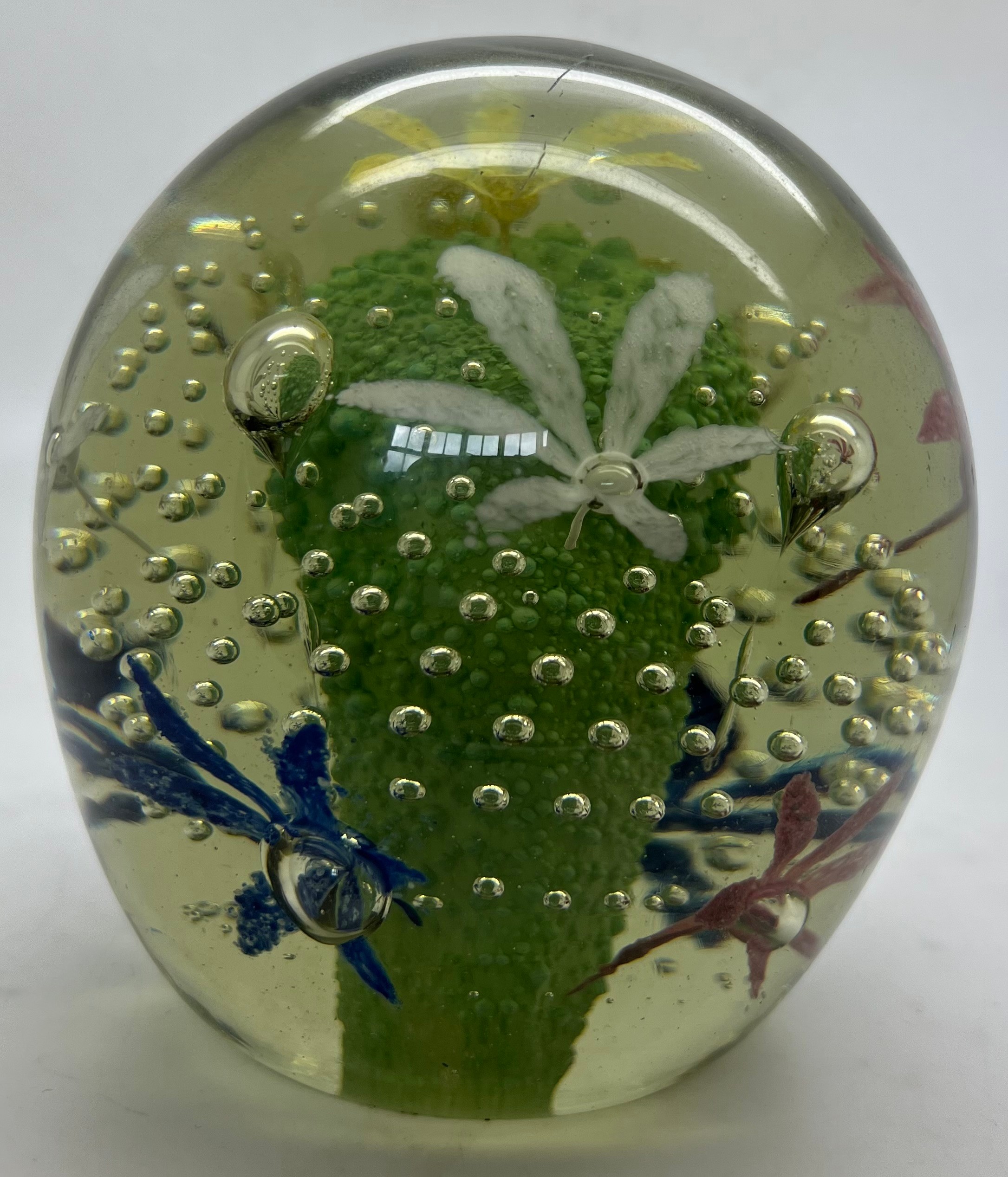 A glass paperweight with central green decoration, flowers and bubbles. 11.5cm h.Condition