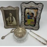 Two silver photograph frames, one modern, a silver topped glass jar, white metal tongs and a