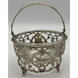 Pierced silver basket with swing handle, vacant cartouche and associated glass liner. Birmingham