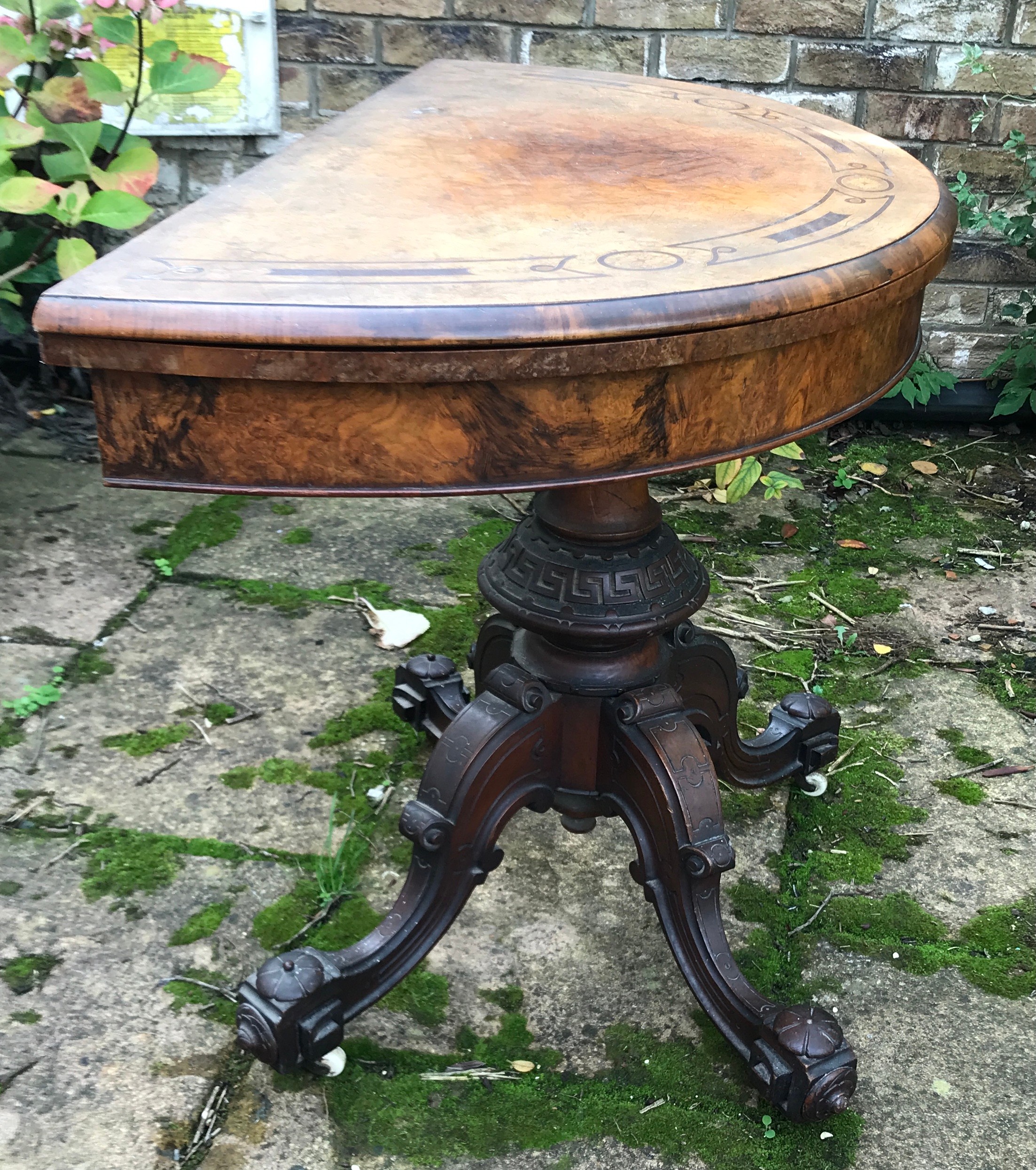 A Victorian walnut demilune card table, hinged top enclosing a baize lined playing surface, turned