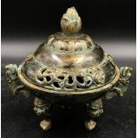 A Chinese bronze incense burner, with lotus finial and dragon handles, raised on three shaped