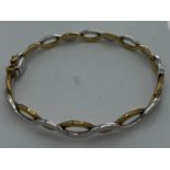 A nine carat yellow and white gold hinged bangle. Weight 10.6gm.