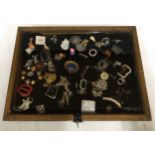 A glass display cabinet displaying an assortment of costume jewellery to include brooches,