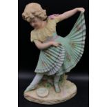 A late 19thC Gebruder Heubach bisque figurine of a girl modelled in a green pleated dress and ballet