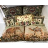 A collection of seven jacquard cushions depicting a camel, an elephant and flowers, largest approx