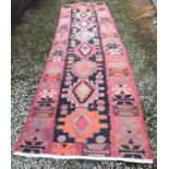 A large red, black and orange Kilim runner 420 l x 123cm w.