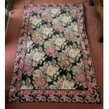 A 20thC tapestry rug, black background with pink and pastel roses. 176 x 226cm.