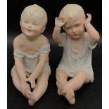 Two Gebruder Heubach piano dolls modelled both seated, one with arms raised 17cm, the other 16cm.