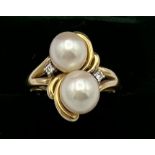 A 14 carat yellow gold ring set with two cultured pearls and two diamonds. Weight 4gm. Size L.
