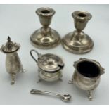 Silver to include three-piece cruet, mustard spoon and a pair of candlesticks with weighted bases,