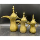 Three graduating Middle Eastern brass coffee pots. Tallest 37cm.