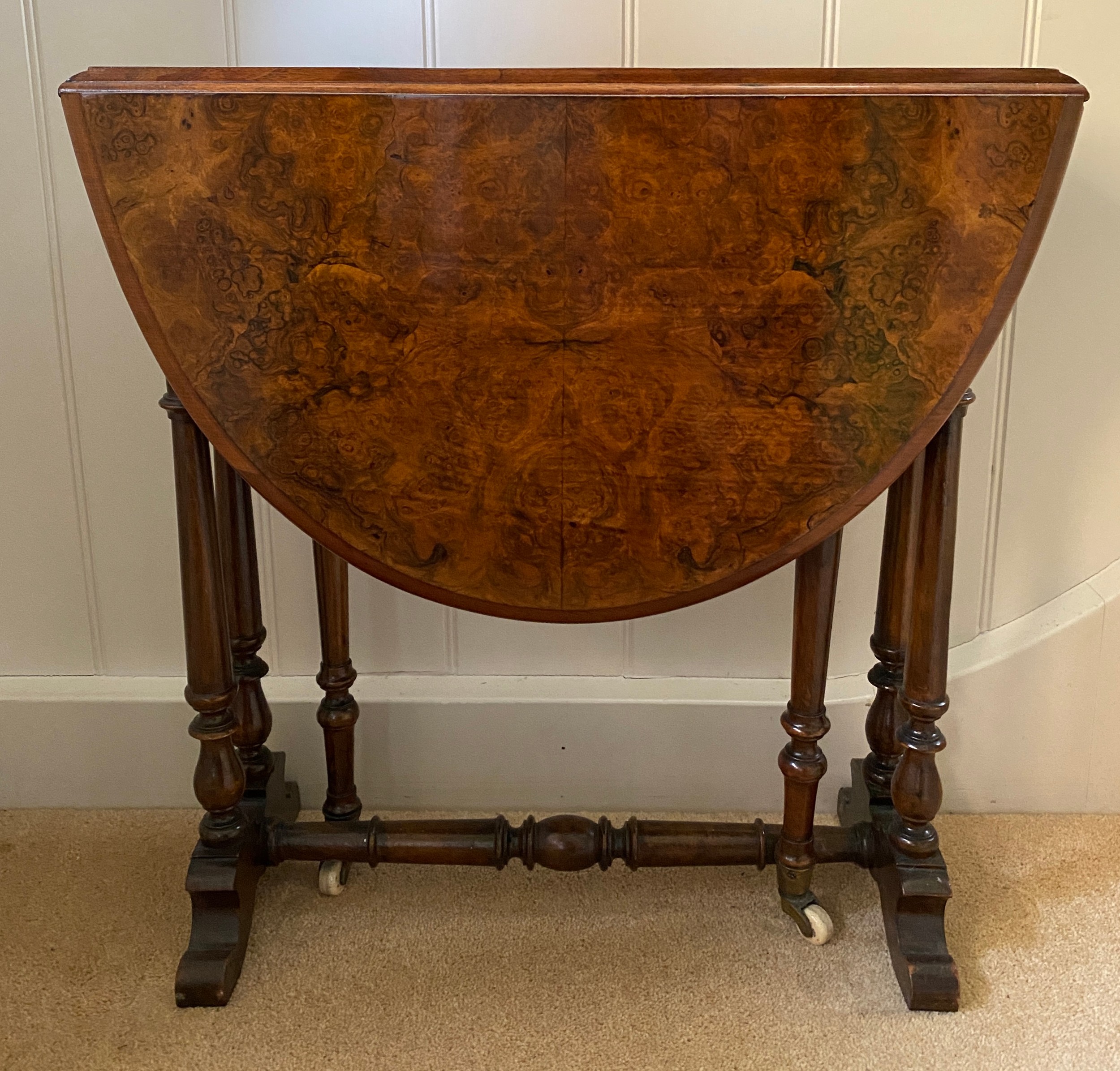 A 19thC burr walnut oval drop leaf table on white porcelain castors. Open 70 x 53 x 53cm h. Closed