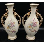 A pair of 19thC vases with painted flowers to front and back with gold gilt handles.