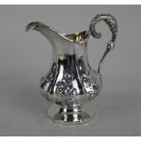 A Victorian silver cream jug facetted form with scroll handle embossed floral decoration, engraved
