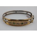 A 9ct gold bangle set with emeralds and small diamonds (a/f one stone missing), 8.7g