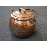 A copper stew pot of bulbous form with cover and swing handle