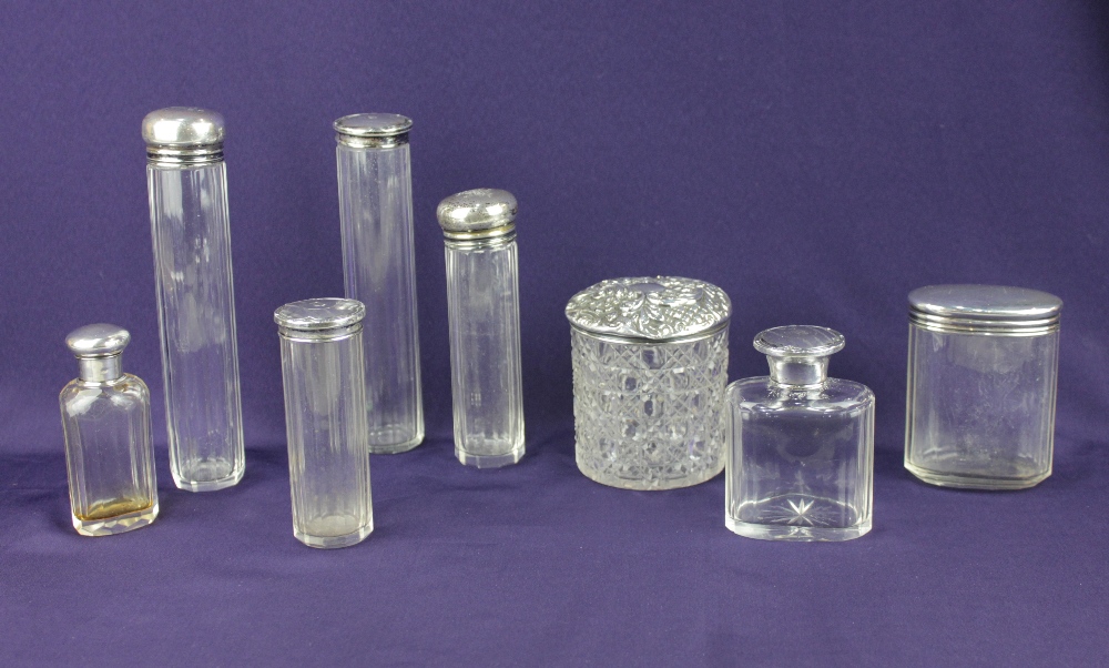 A collection of eight various silver lidded glass dressing table jars some with engraved intials,