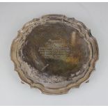 A modern silver salver with pie crust border on four scroll feet, presentation inscription, maker