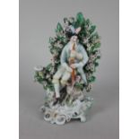 A Derby porcelain bocage figure of a gentleman playing bagpipes with a dog at his feet, on scroll