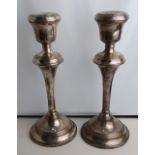 A pair of silver candlesticks with urn sconces on flared stems and loaded circular bases,