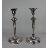 A pair of silver plated candlesticks with urn shaped sconces on tapered stems and circular bases