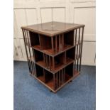 An Edwardian inlaid mahogany revolving bookcase, with three tiers and slatted sides, on cruciform