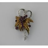 An 18ct white and yellow gold ruby and diamond set floral brooch on ribbon mount, 4.5cm