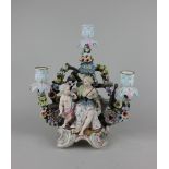 A Sitzendorf porcelain three light figural candelabrum of a seated woman and Cupid against floral