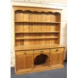 A large pine dresser with top of carved cornice and two shelves above three drawers, open dog kennel