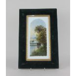 A porcelain hand painted panel decorated with a scenic river landscape, in velvet cushion frame,
