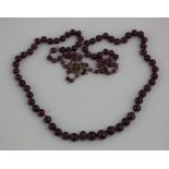 A ruby bead necklace with an extender chain in 14ct gold, with an ornate gem set clasp
