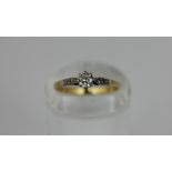 A diamond single stone ring, claw set with smaller shoulder stones in white and yellow gold