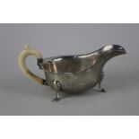 A George V silver sauce boat with shaped border on three scroll feet, maker Viners Sheffield 1935,