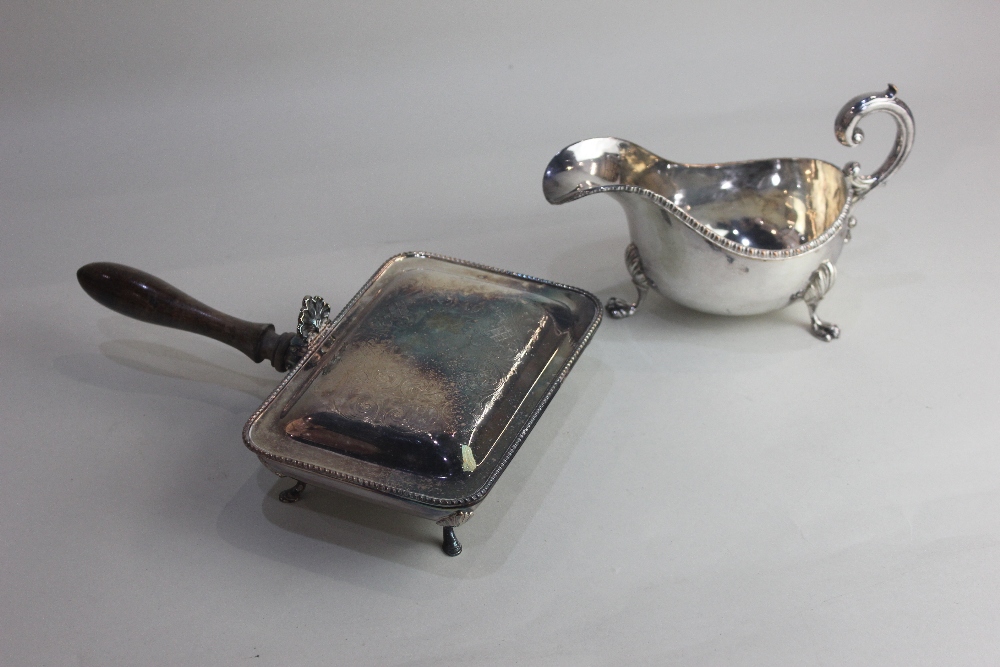 A silver plated sauce boat with flying scroll handle on three paw feet, and a chestnut warming pan