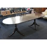 A Regency style mahogany oval dining table with two extra leaves on twin pedestal bases, each with