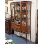 An Edwardian inlaid mahogany display cabinet with bowfronted centre flanked by two doors enclosing