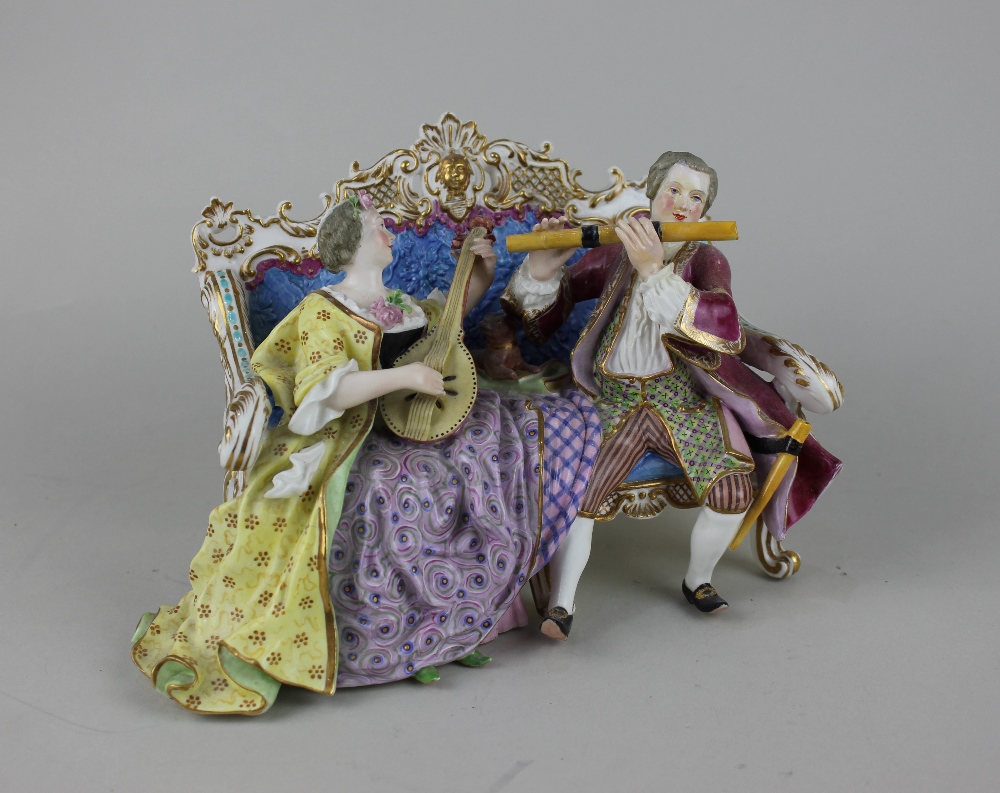 A Meissen style porcelain figure group of two musicians seated on a couch, him playing a flute,