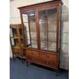 An Edwardian mahogany and inlaid display cabinet with two glazed panel doors enclosing three glass