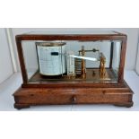 An oak cased barograph by Negretti & Zambra, London, no. 30323, centred with a thermometer, glass