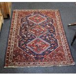 A Qashqai type rug, red ground, with central repeating diamond motif amongst animals within multiple