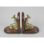A pair of mahogany and brass dolphin bookends 16cm high