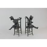 A pair of bronze figures of seated children, one with a cat, stamped 'A7306' and 'A7307',