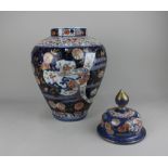 A large Japanese Imari porcelain vase and cover decorated with panels of landscapes amongst flowers,
