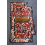 A saddle rug, probably Tibetan, red ground, decorated with two dragons within a patterned border