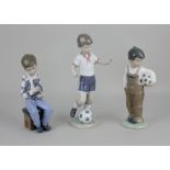 A Lladro porcelain figure of a boy footballer 22cm high, together with two Nao porcelain figures
